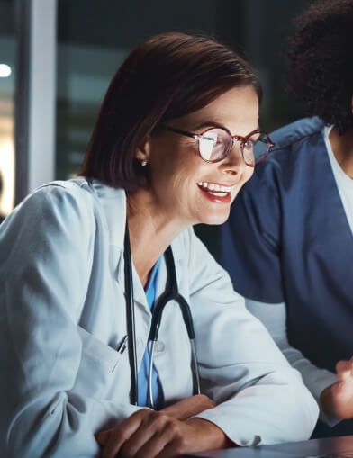 Smiling woman in a lab coat looking at a screen