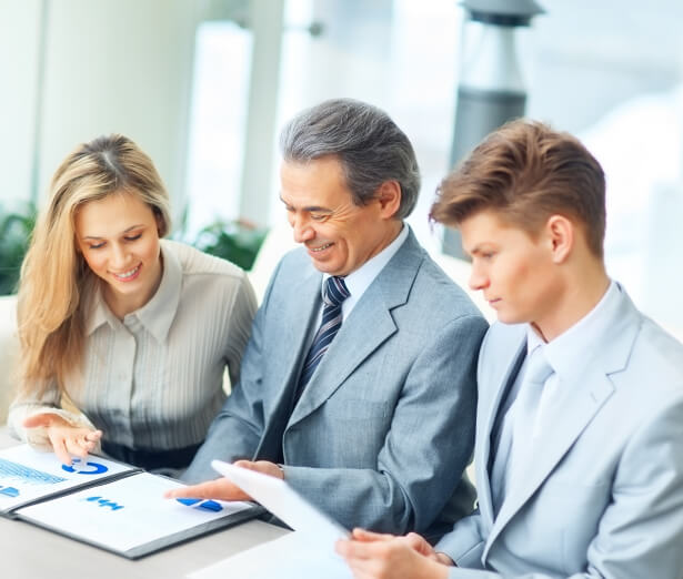 Three people reviewing charts and documents at a table